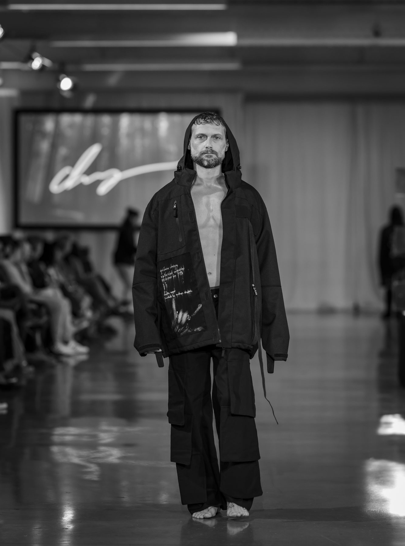 Patrice Labasse sur le podium, veste noire à capuche, noir et blanc