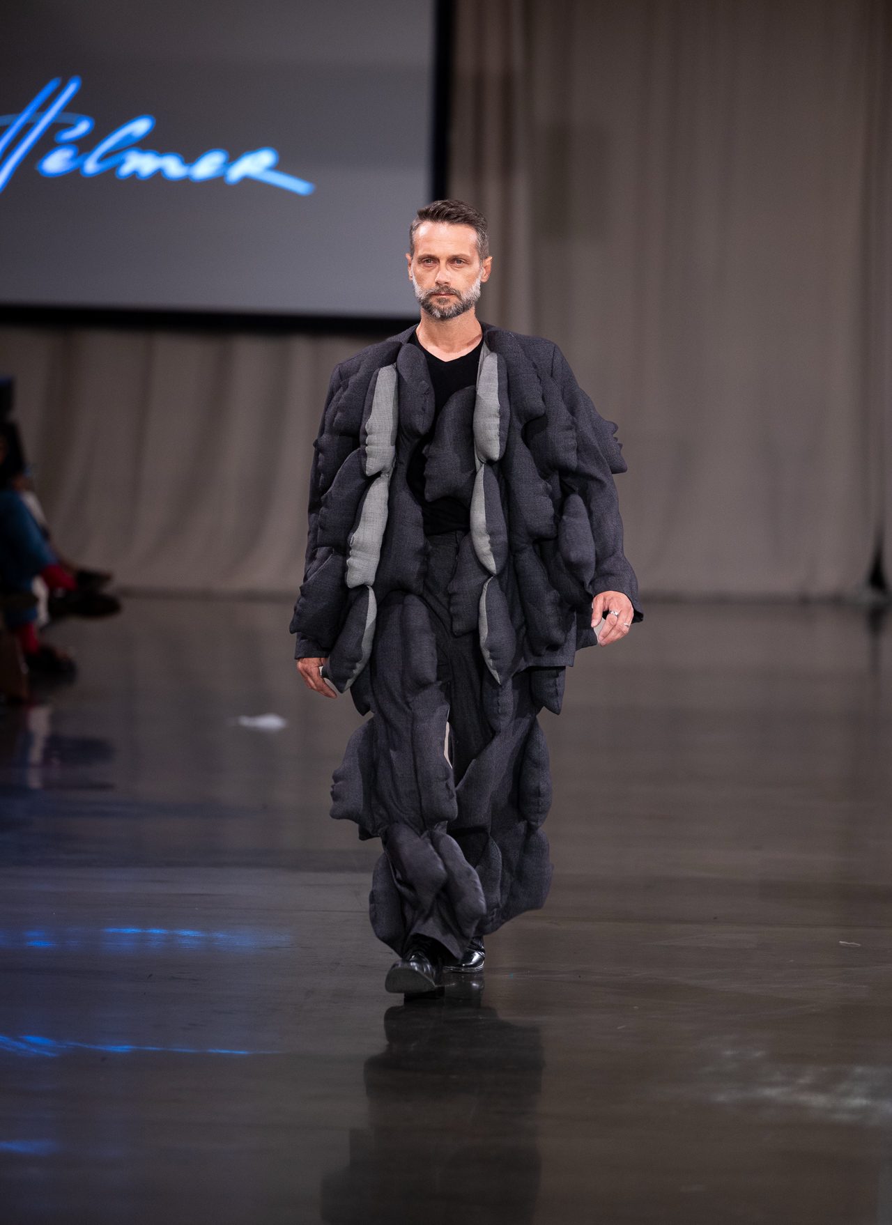 Patrice Labasse sur le podium, tenue avant-gardiste noire