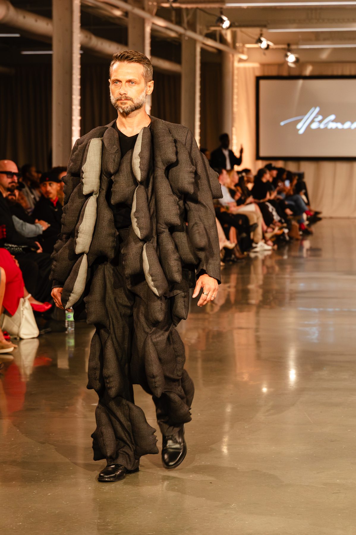 Patrice Labasse sur le podium, tenue avant-gardiste noire